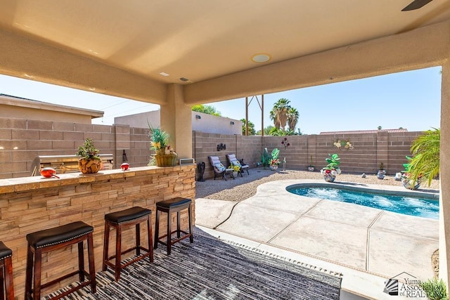 view of swimming pool featuring a fenced in pool, a fenced backyard, a patio area, and outdoor dry bar