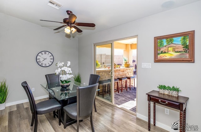 dining area featuring baseboards, ceiling fan, wood finished floors, and visible vents