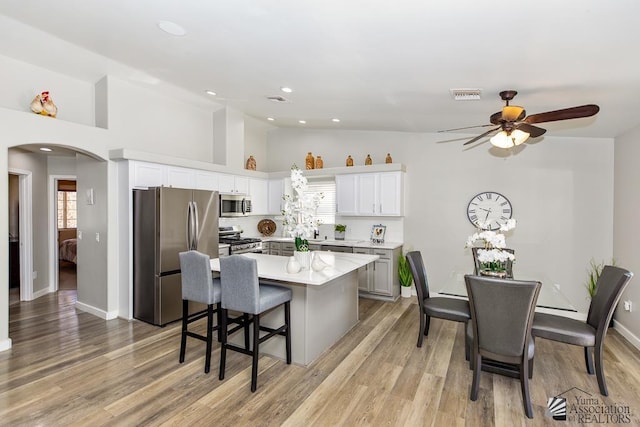 kitchen with visible vents, lofted ceiling, ceiling fan, arched walkways, and stainless steel appliances