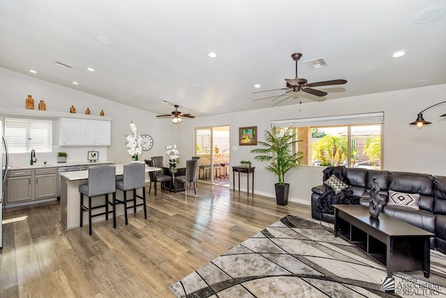 living area with a ceiling fan, visible vents, wood finished floors, lofted ceiling, and recessed lighting