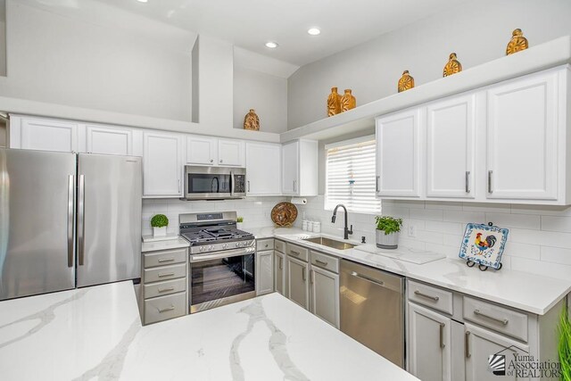 kitchen featuring decorative backsplash, a sink, light stone counters, stainless steel appliances, and recessed lighting