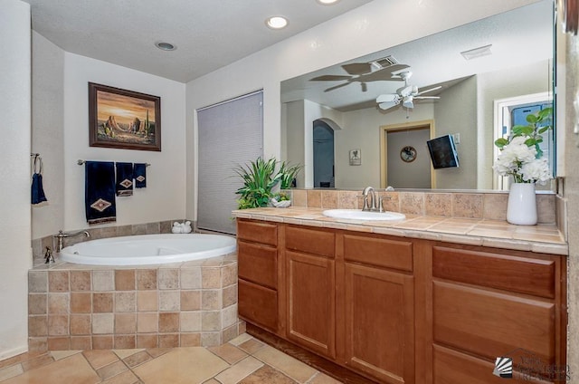 bathroom with a garden tub, ceiling fan, visible vents, and vanity