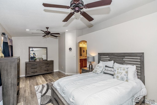 bedroom featuring recessed lighting, arched walkways, baseboards, and wood finished floors