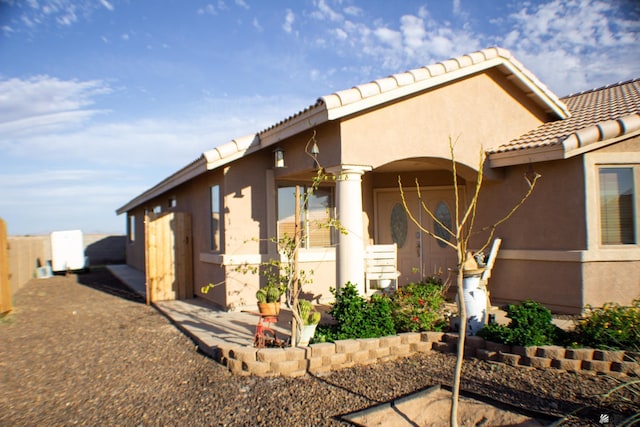 view of property exterior with a tiled roof, fence, and stucco siding