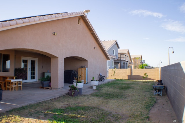 rear view of house with a fenced backyard, stucco siding, french doors, a patio area, and a tiled roof