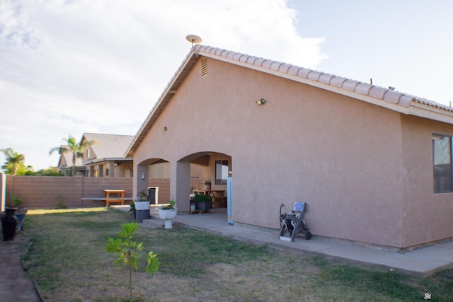 rear view of house featuring fence, a patio, stucco siding, and a yard