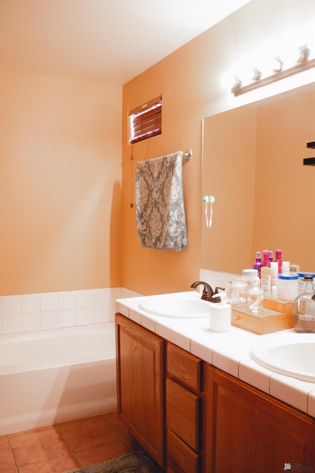 full bath featuring double vanity, tile patterned floors, a sink, and a garden tub