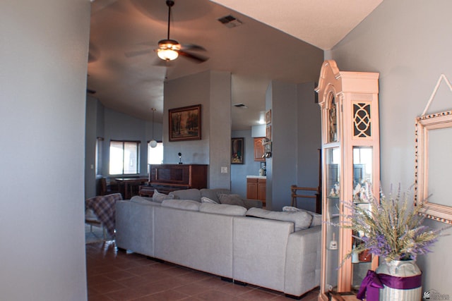 living area featuring a ceiling fan, visible vents, dark tile patterned floors, and vaulted ceiling
