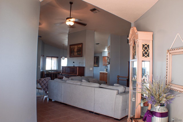 living room featuring vaulted ceiling, dark tile patterned flooring, a ceiling fan, and visible vents