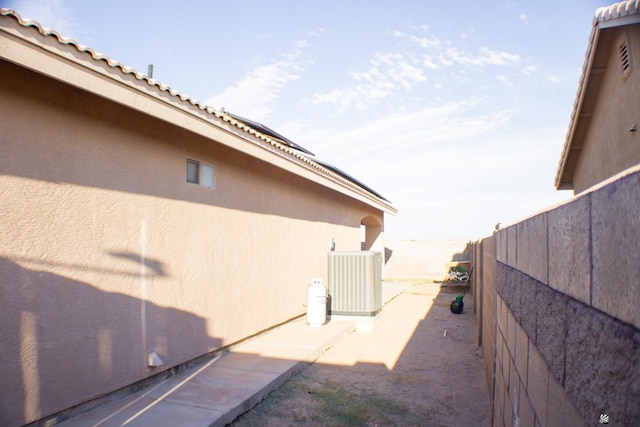 view of side of property with central air condition unit, fence, and stucco siding