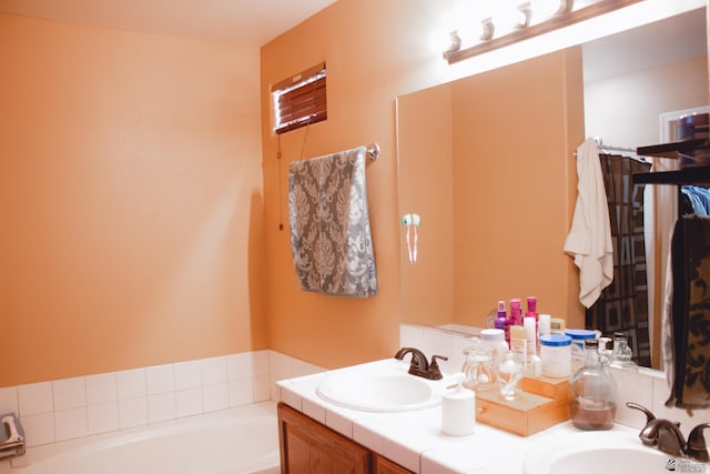 full bathroom featuring double vanity, a sink, and a garden tub