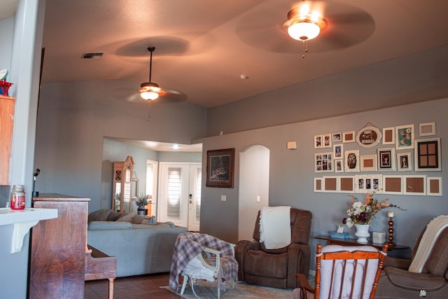 living room with dark tile patterned floors, ceiling fan, visible vents, arched walkways, and vaulted ceiling