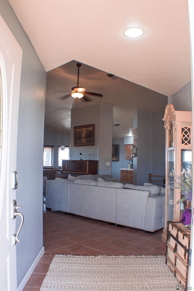 living room with dark tile patterned floors, baseboards, ceiling fan, and lofted ceiling