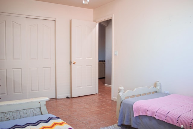 bedroom featuring light tile patterned floors, baseboards, and a closet