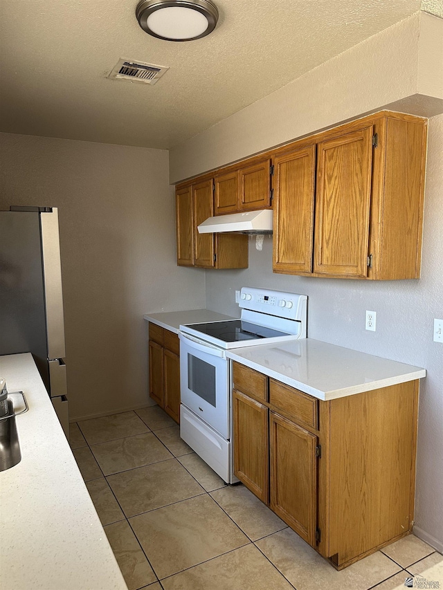 4732 W 17th Ln, Yuma, AZ 85364 - kitchen with white electric range oven, under cabinet range hood, brown cabinets, light countertops, and light tile patterned floors