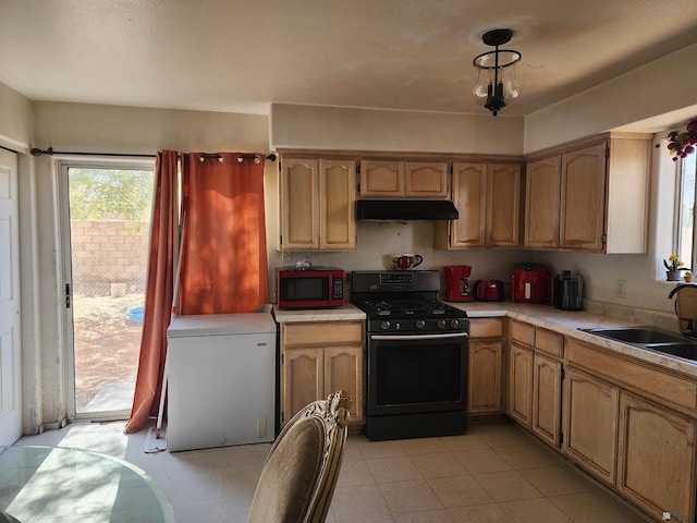 kitchen with light countertops, gas stove, a sink, white fridge, and under cabinet range hood