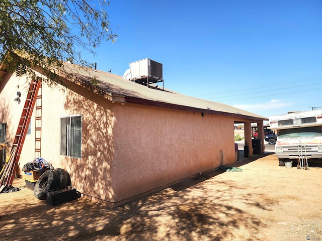 view of side of property with central AC unit and stucco siding