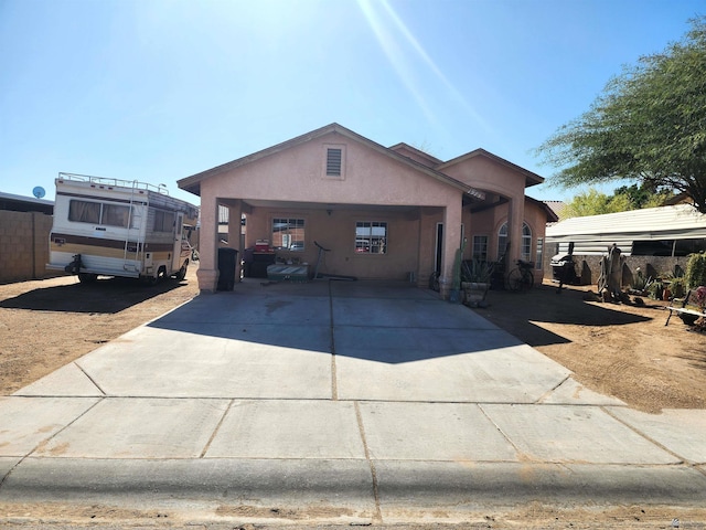 view of front of home with concrete driveway, fence, and stucco siding