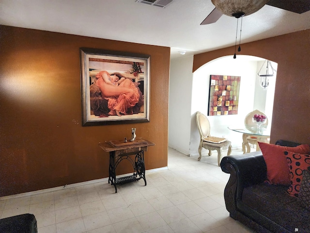 living area with ceiling fan, arched walkways, and baseboards