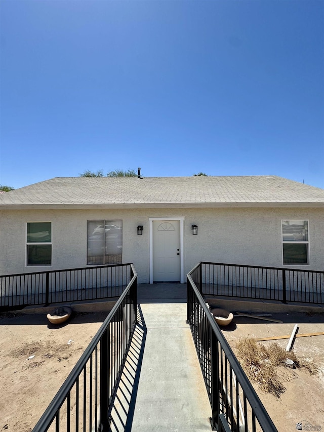 view of front of house featuring roof with shingles and stucco siding
