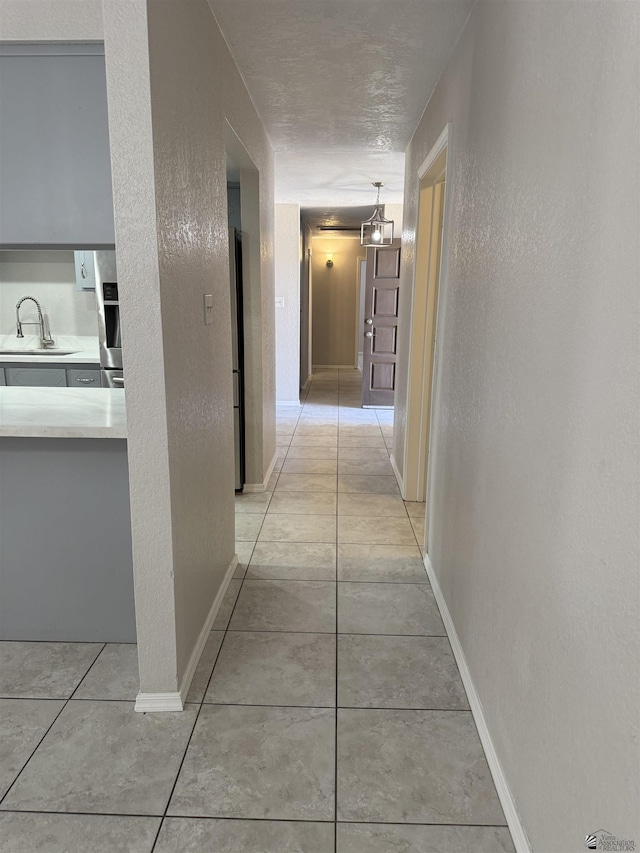 1435 S Thomas Ave, Yuma, AZ 85364 - hall featuring a sink, a textured wall, baseboards, and light tile patterned floors