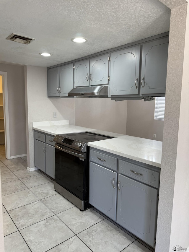 1435 S Thomas Ave, Yuma, AZ 85364 - kitchen with gray cabinets, electric stove, under cabinet range hood, a textured ceiling, and light tile patterned floors