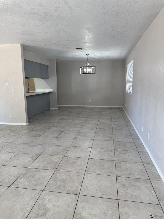 1435 S Thomas Ave, Yuma, AZ 85364 - unfurnished living room with a textured ceiling, baseboards, and light tile patterned flooring