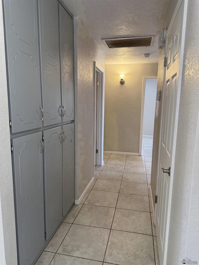 1435 S Thomas Ave, Yuma, AZ 85364 - corridor featuring a textured wall, light tile patterned flooring, a textured ceiling, attic access, and baseboards