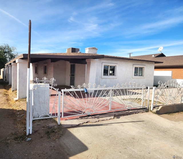 view of front of property featuring a gate, a fenced front yard, stucco siding, and a chimney