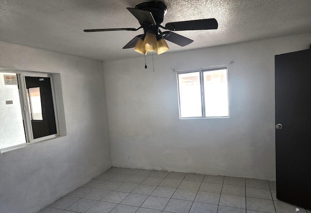 unfurnished room featuring a textured ceiling, ceiling fan, and light tile patterned floors