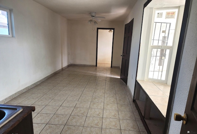 empty room with light tile patterned floors and a ceiling fan
