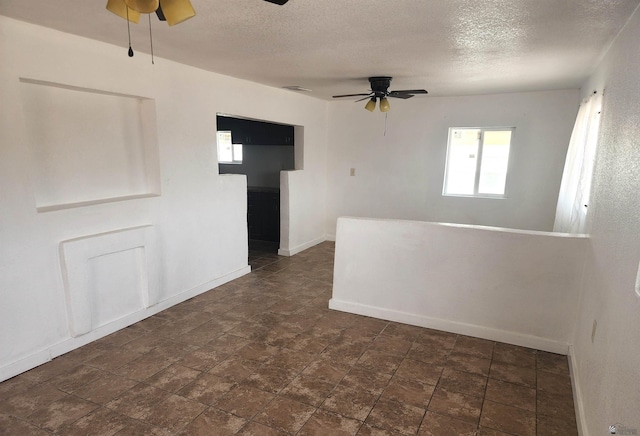 empty room with baseboards, ceiling fan, and a textured ceiling