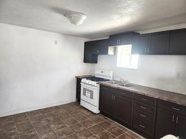 kitchen with a sink, baseboards, white range with gas cooktop, and a textured ceiling