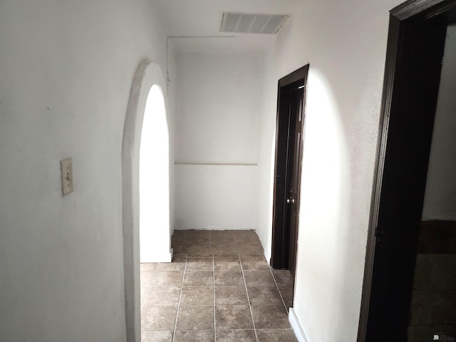 hall featuring arched walkways, stone finish flooring, and visible vents