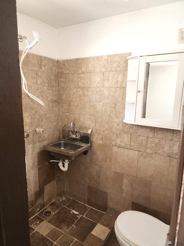 bathroom with a sink, a tile shower, and toilet