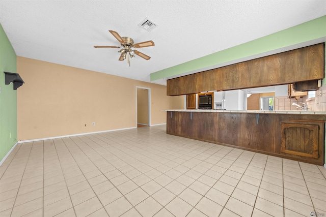 1228 S 40th Dr, Yuma, AZ 85364 - kitchen with white fridge with ice dispenser, a ceiling fan, black microwave, light countertops, and baseboards