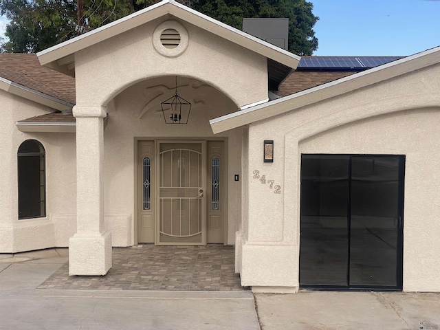 2472 S 18th Ave, Yuma, AZ 85364 - entrance to property featuring stucco siding, a shingled roof, and roof mounted solar panels