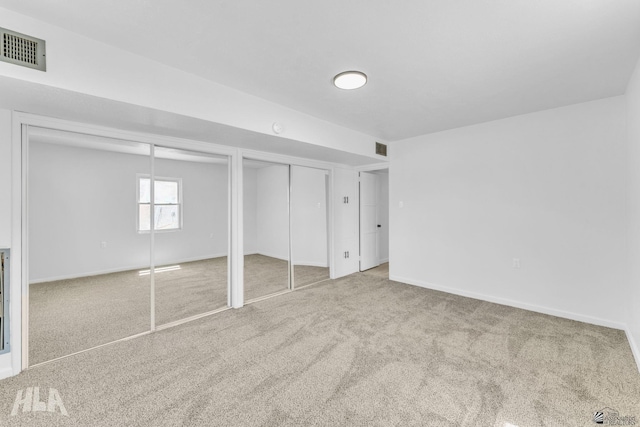 unfurnished bedroom with carpet floors, baseboards, two closets, and visible vents