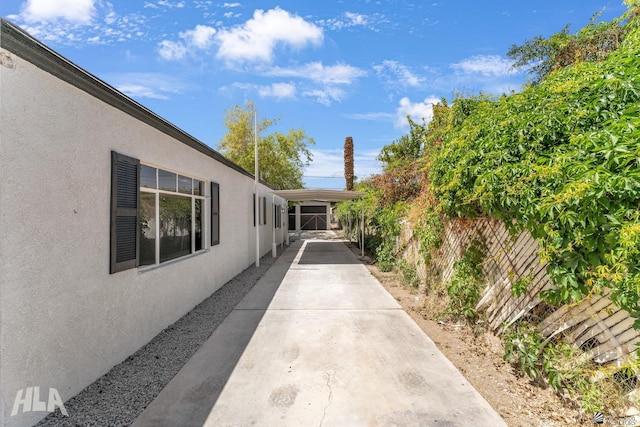 view of side of home featuring stucco siding and fence