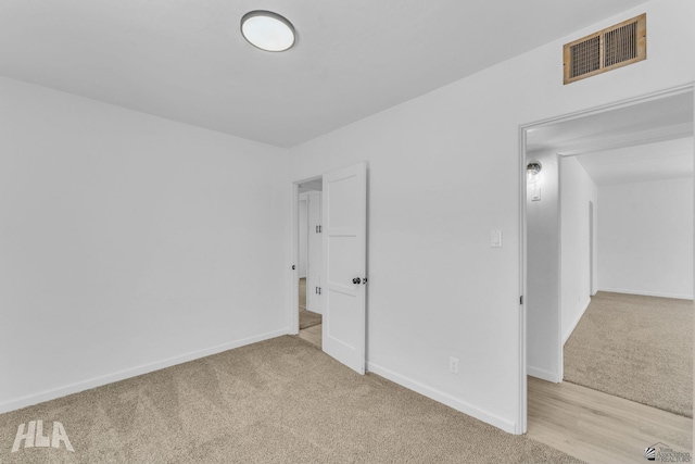 unfurnished bedroom featuring light colored carpet, baseboards, and visible vents