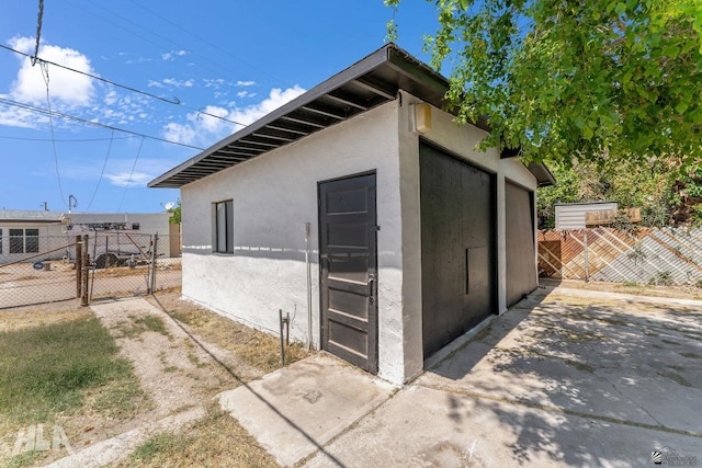 view of outbuilding featuring fence and a gate