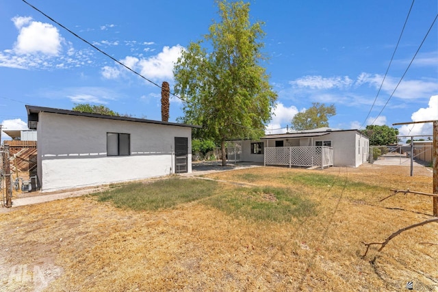 rear view of property featuring a lawn and fence