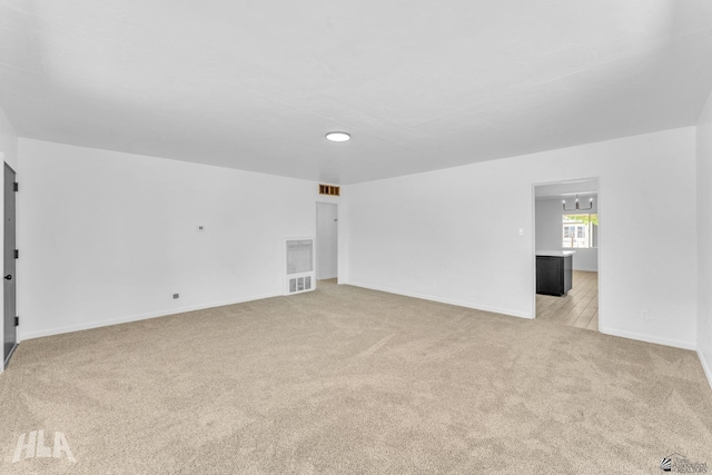 interior space with light colored carpet, baseboards, and visible vents