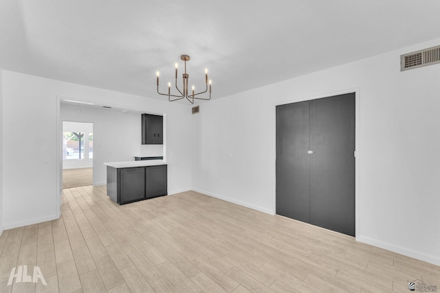 interior space featuring visible vents, light wood-style flooring, baseboards, and a notable chandelier