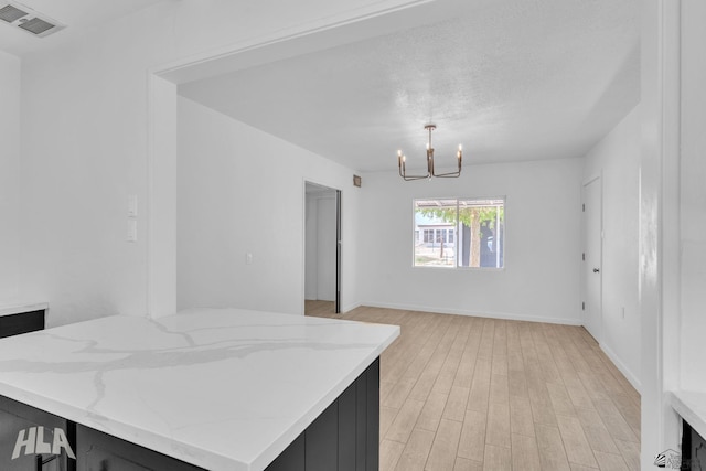 dining space with visible vents, light wood-style floors, baseboards, and a notable chandelier