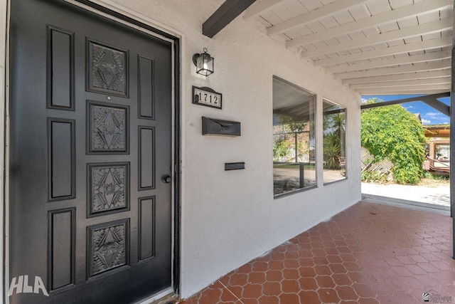 entrance to property with covered porch and stucco siding