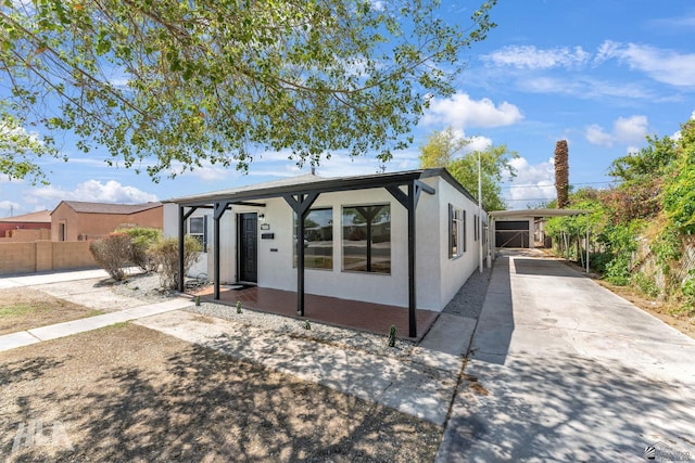 view of front of house with stucco siding, fence, driveway, and a carport