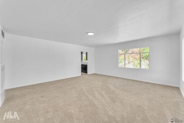 unfurnished living room with baseboards, visible vents, and carpet