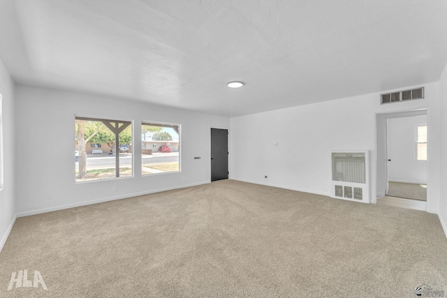 carpeted empty room featuring baseboards, visible vents, and a healthy amount of sunlight