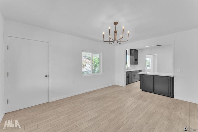 interior space featuring light wood-style floors, baseboards, and a chandelier